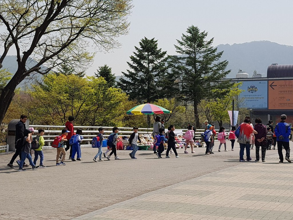 서울대공원 입구 광장을 걸어가는 아이들과 가족 나들이객